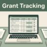 An open laptop showing a grant tracking dashboard next to proposal documents.