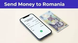 A smartphone shows a money transfer confirmation beside a Romanian banknote.