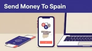 Phone showing a money transfer beside a laptop and passport under a Spain banner.