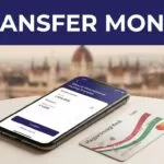 A smartphone with a money transfer screen beside a Hungarian bank card.