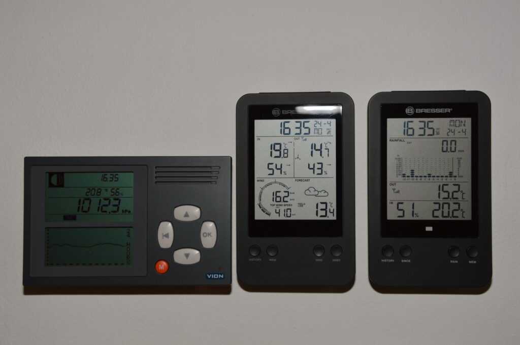Multiple digital weather monitors display temperature and pressure readings.