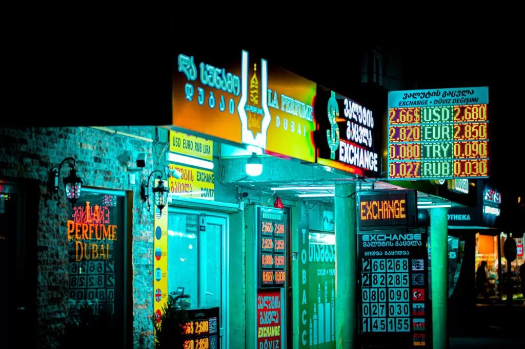 Night view of a brightly lit storefront and currency exchange signs in Batumi, Georgia.
