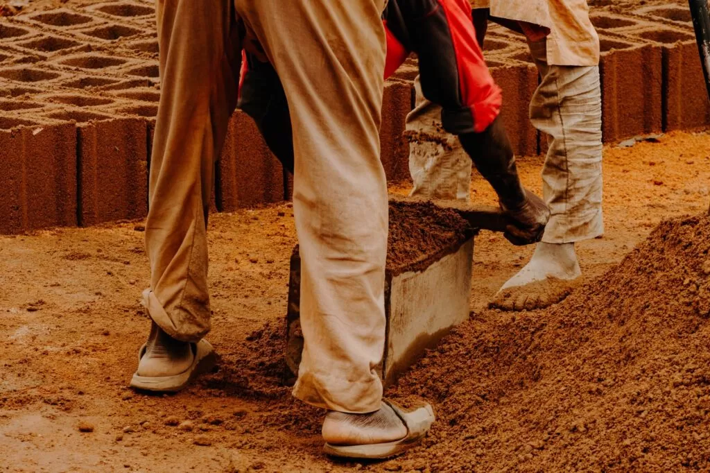 Workers using molds to shape eco-friendly bricks in an outdoor setting.