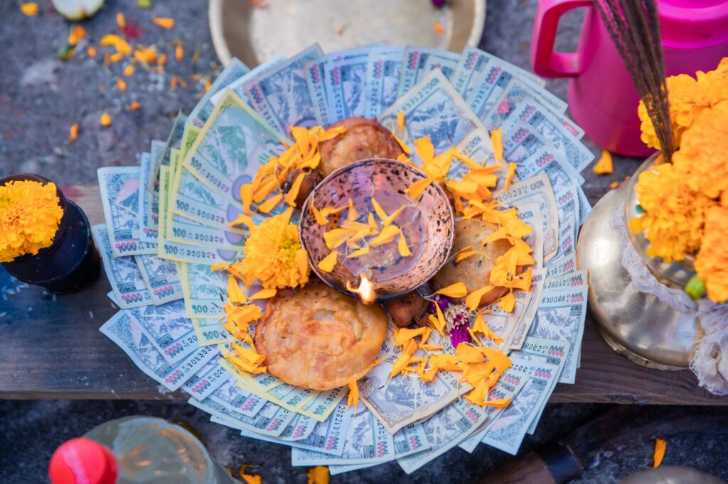 A colorful arrangement of Nepalese rupees, marigold flowers, and traditional sweets during a cultural festival.